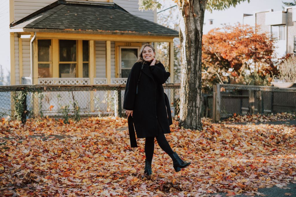 A photo of a woman frolicking in the leaves